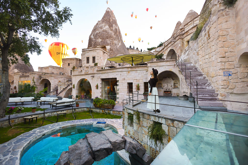 Guest in the Anatolian Houses courtyard, balloons over the fairy chimneys